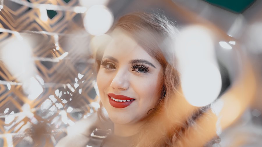 Portrait through fairy light bokeh — red lips golden glow