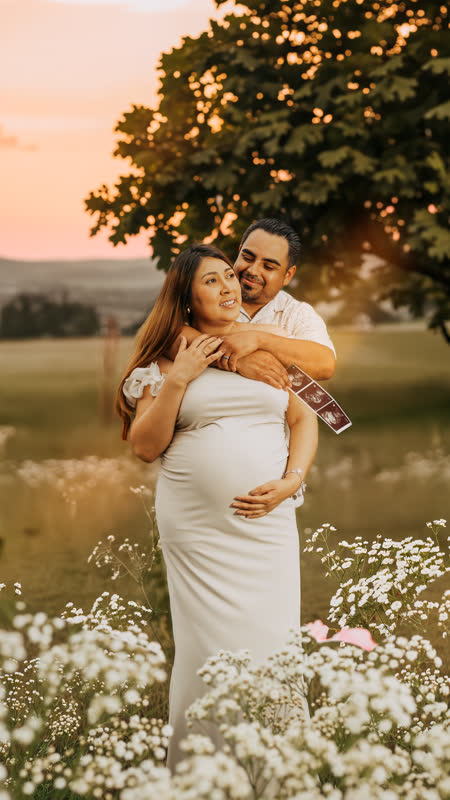 Sunset maternity session, couple holding sonogram in wildflower field