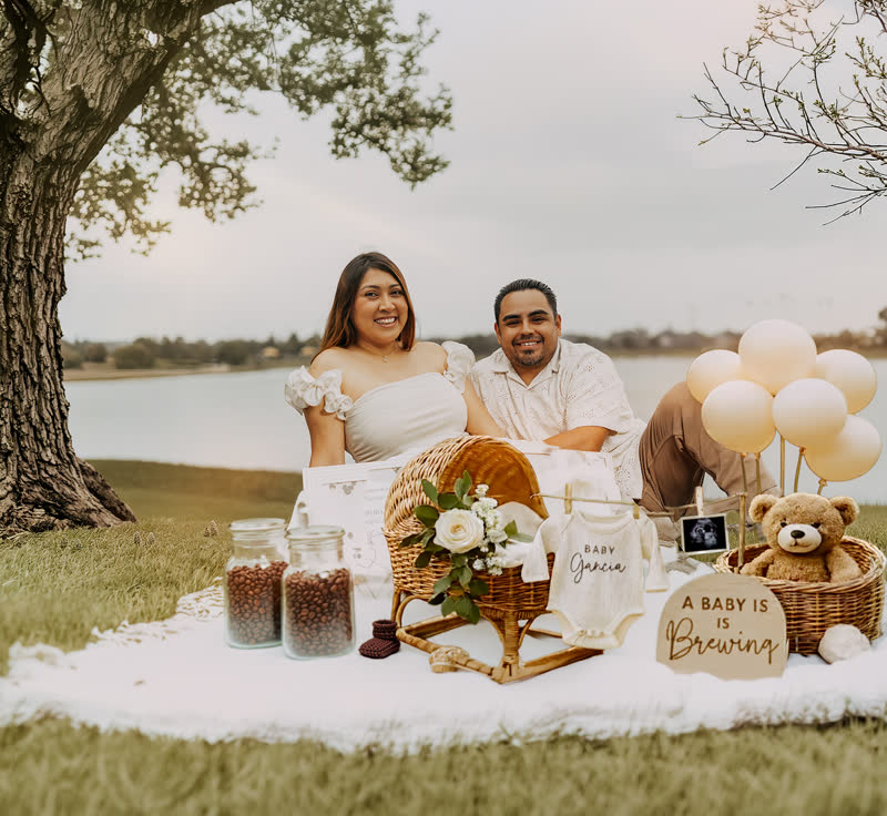 Couple at lakeside picnic baby announcement setup